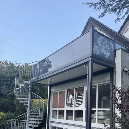 Moderne Anbauten mit Wendeltreppe an einem traditionellen Haus unter blauem Himmel